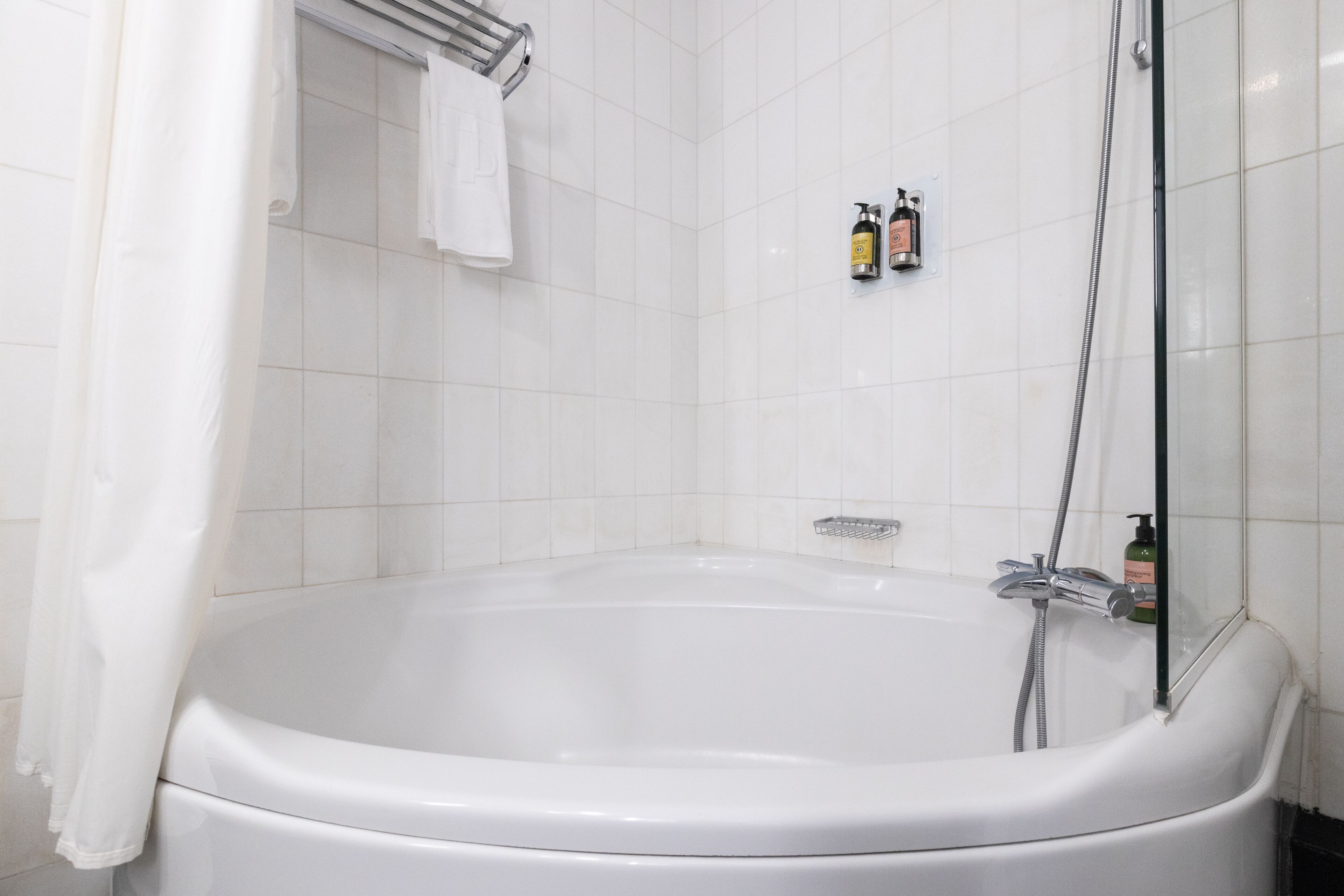 A modern bathroom with a large bathtub, a glass shower enclosure, and a towel rack.