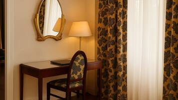 Una habitación de hotel con escritorio, silla, lámpara y espejo.