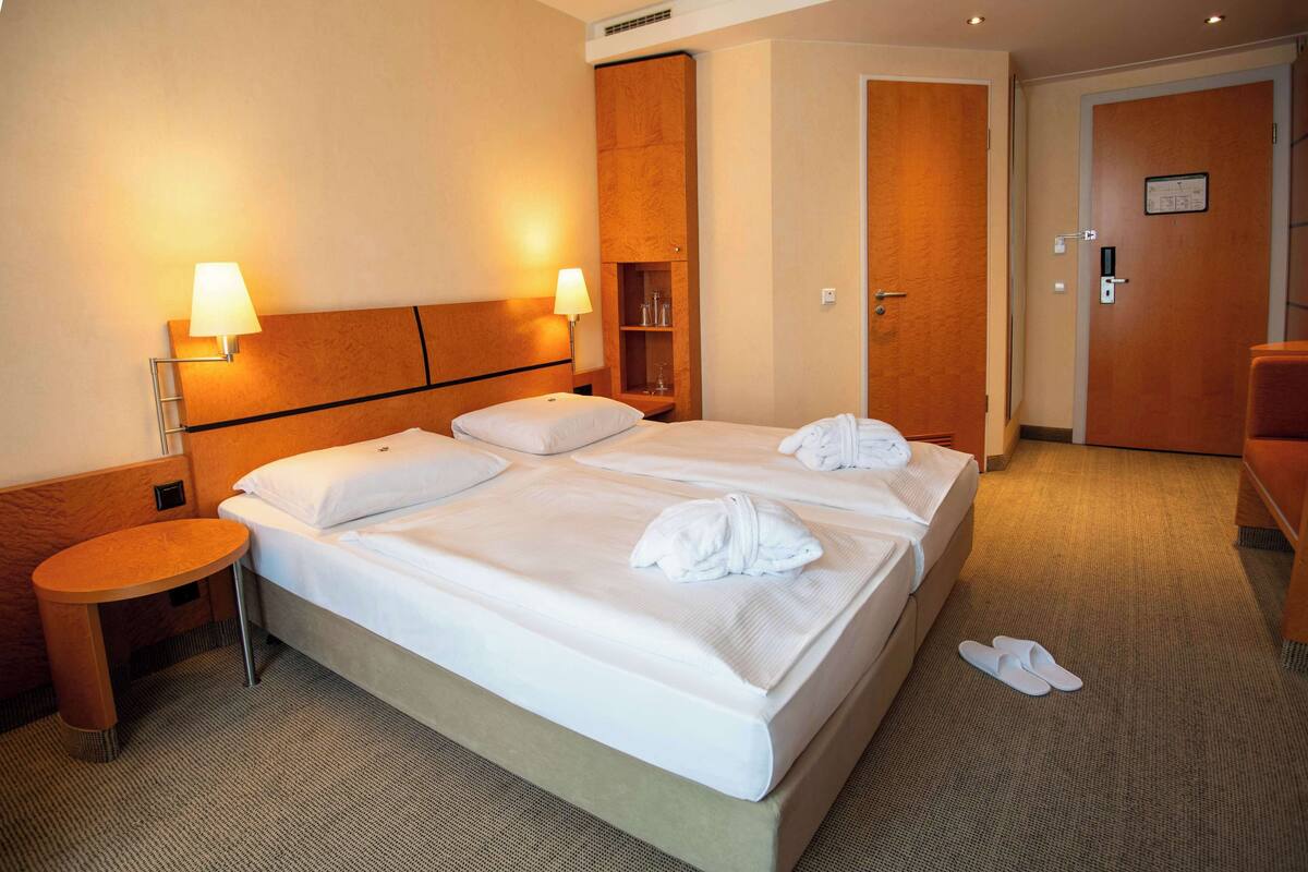 Een hotelkamer met een groot bed, twee nachtkastjes, een klein rond tafeltje en een kledingkast.