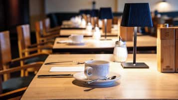 Un comedor con mesas dispuestas para una ceremonia de té, incluyendo tazas, platitos y cucharas.