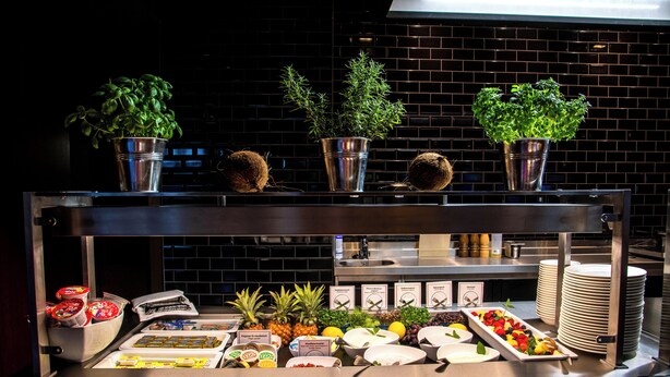 A buffet with various food items and potted plants.