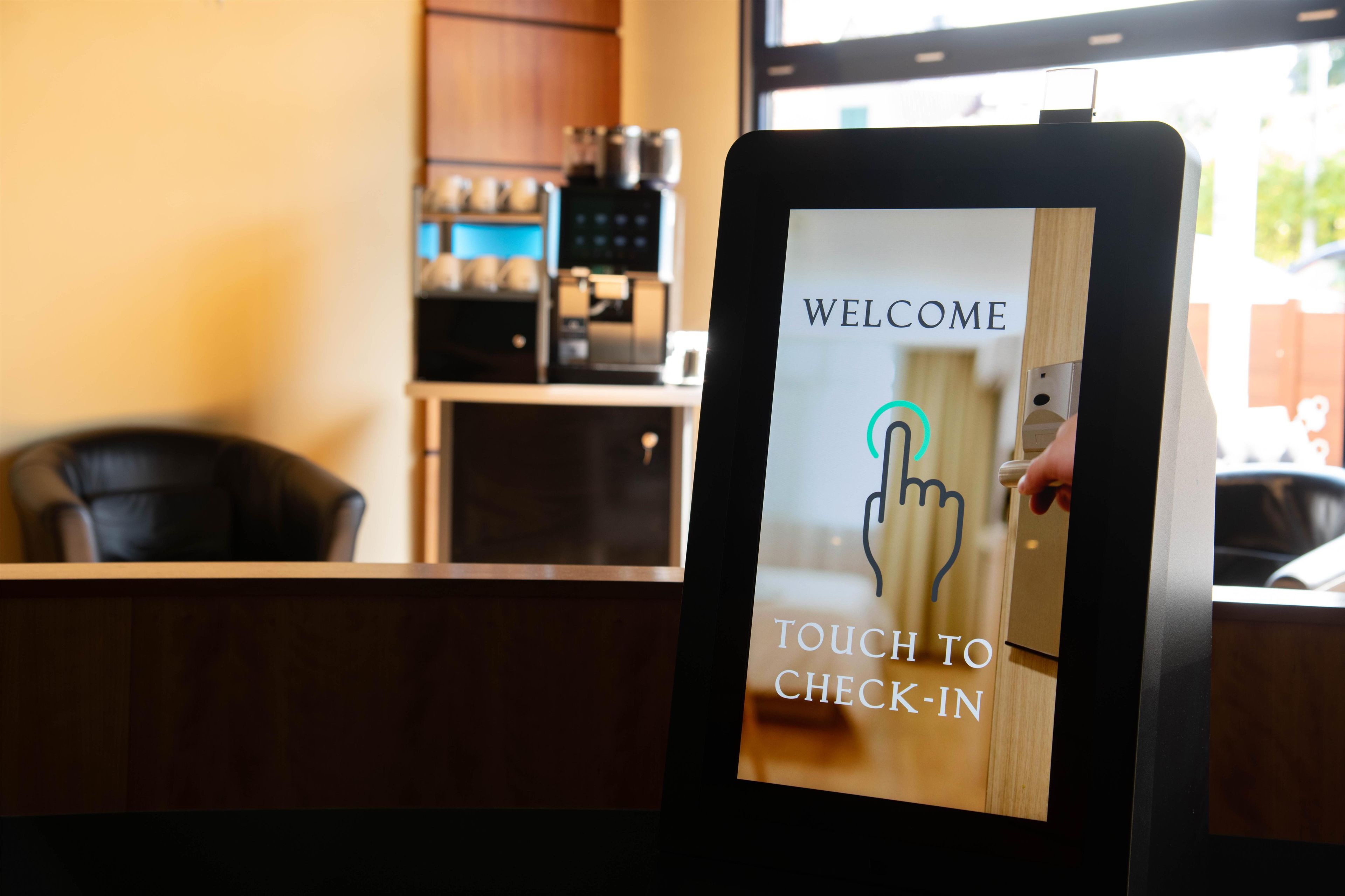 A digital kiosk with a 'WELCOME TOUCH TO CHECK-IN' message.