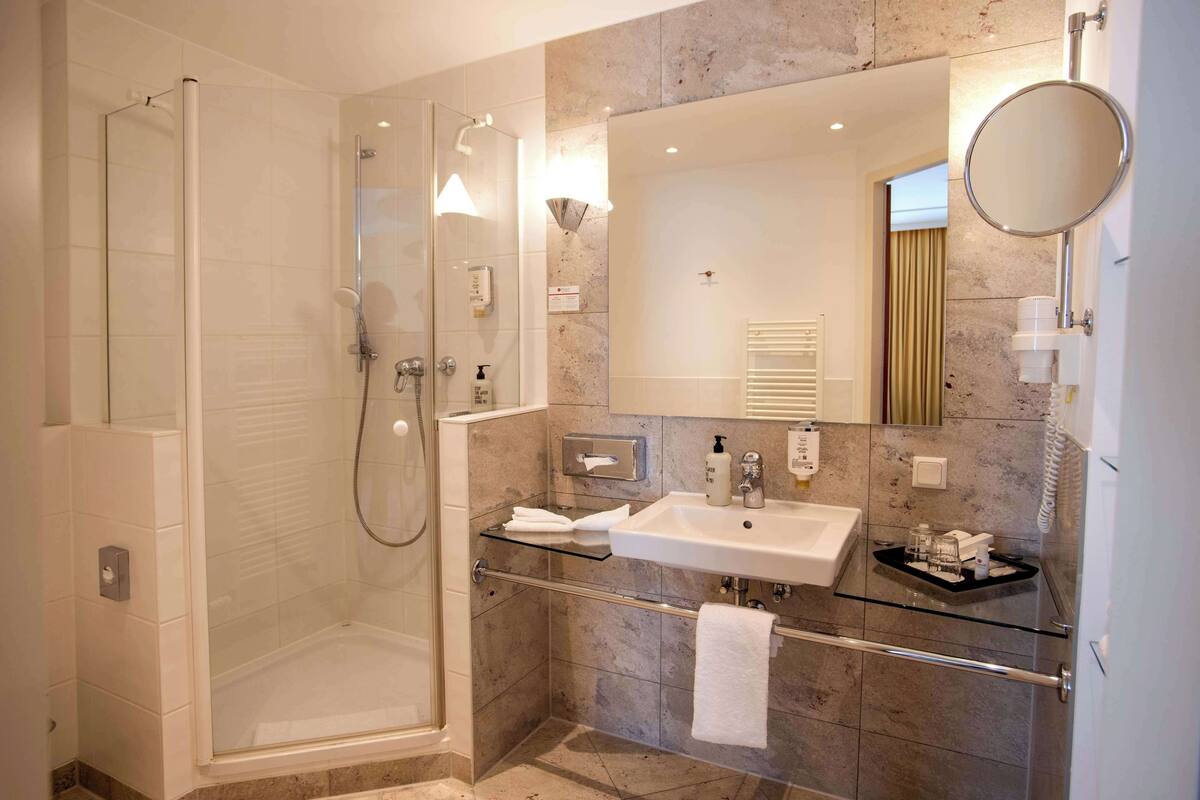 Een moderne badkamer met een douchecabine van glas, een wastafelmeubel met een wastafel en een grote spiegel.