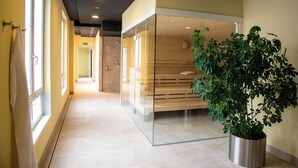 A modern hallway with glass partitions, a potted plant, and a bench.