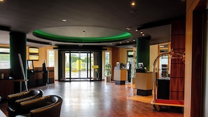 A hotel lobby with a reception desk, seating area, and a luggage cart.