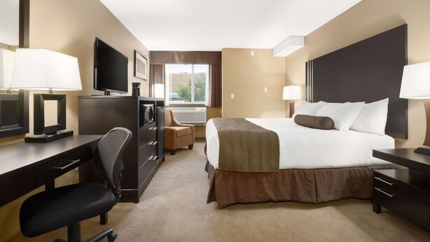 Une chambre d’hôtel équipée d’un lit, d’un bureau, d’une chaise, d’une télévision et d’une fenêtre avec des rideaux.