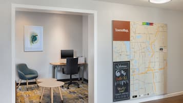 Een hotelkamer met een bureau, stoel en een grote kaart aan de muur.