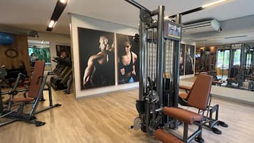 A gym with exercise equipment, wooden flooring, and motivational posters on the walls.
