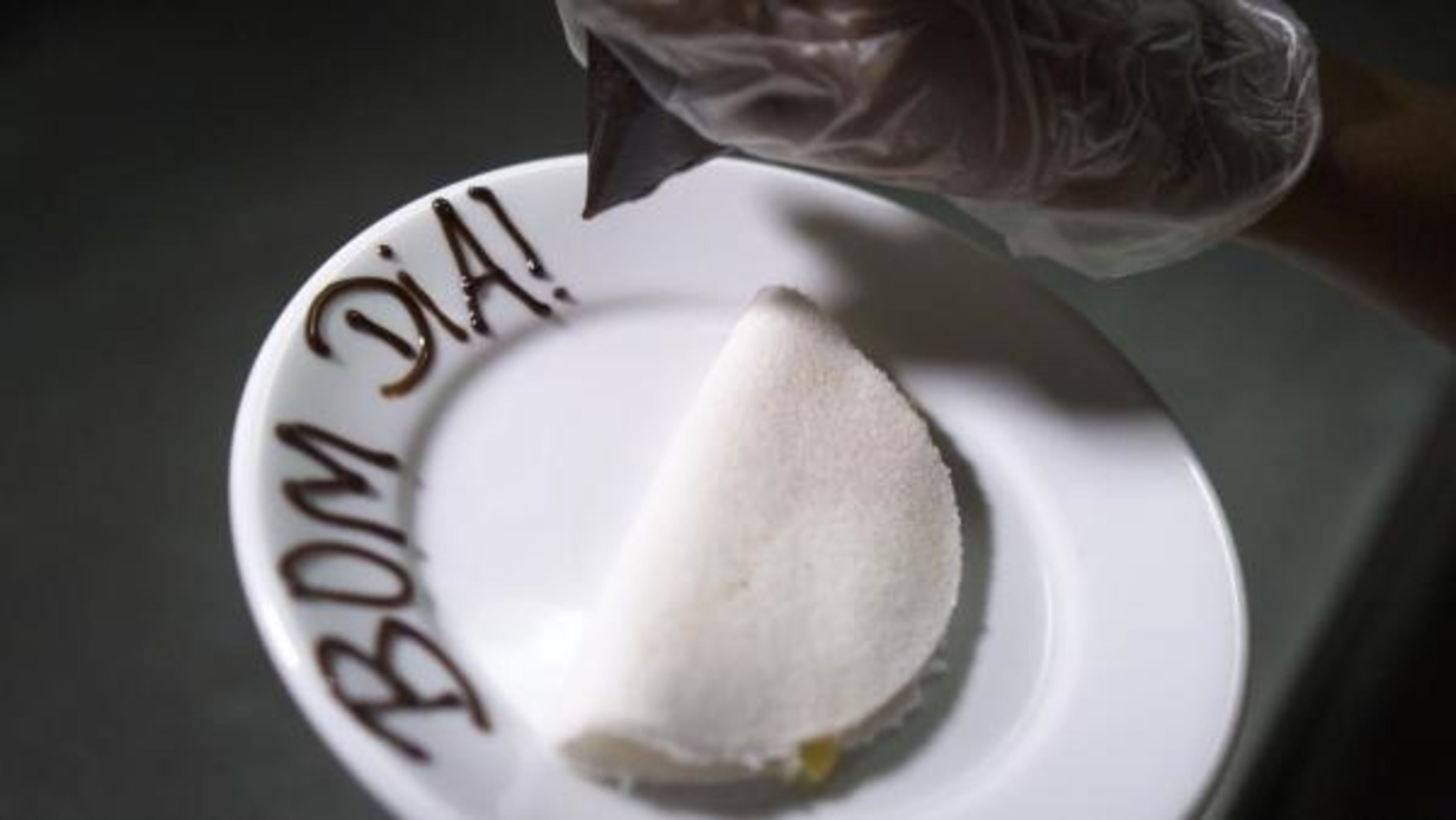Um prato branco com uma substância branca, possivelmente comida, e o texto "BOM JIA!" escrito no prato.