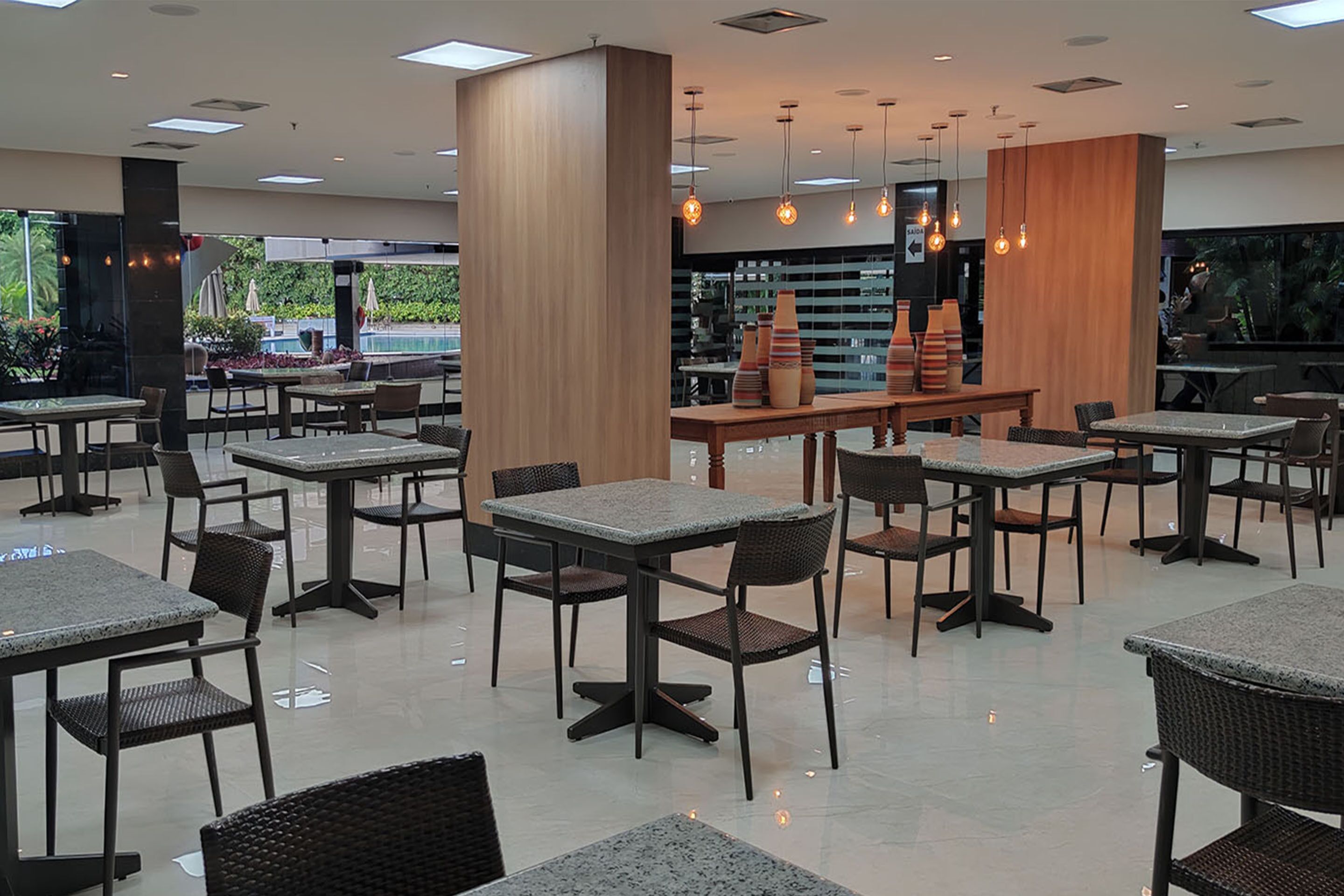 A spacious indoor dining area with multiple tables and chairs, a central counter, and hanging pendant lights.