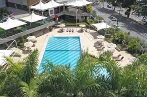 Una piscina al aire libre, sombrillas, sillones reclinables de piscina