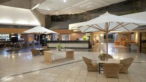 A spacious lobby with a reception desk, seating areas, and large umbrellas.