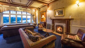 Una habitación acogedora con chimenea, sofás de cuero y un gran ventanal con cortinas.