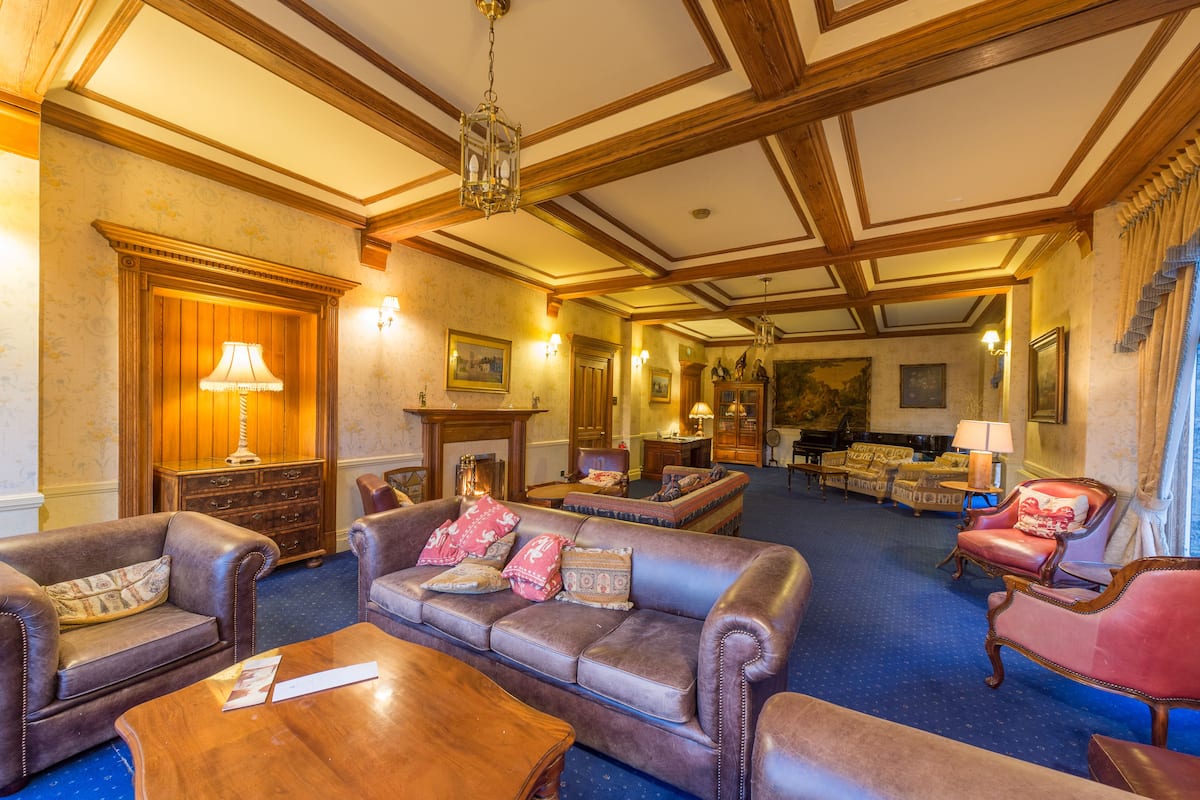 A spacious lobby with leather sofas, wooden furniture, and a fireplace.
