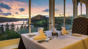 Mesa dispuesta para comer con vistas a un lago y colinas.