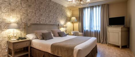 A bedroom with a large bed, a nightstand with a lamp, a TV, and a stone-patterned wall.