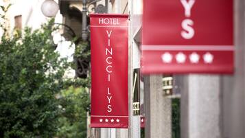 Une enseigne rouge indiquant le nom de l’hôtel « VINCCI LYS » et affichant un classement cinq étoiles.