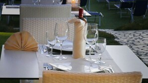 A table set for dining with a view of the sea, outdoor umbrellas, and chairs arranged for guests. - Scoglio della Galea Village & Spa (Ricadi)