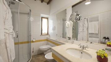 Un baño con cabina de ducha de vidrio, inodoro, lavabo con espejo y ventana.