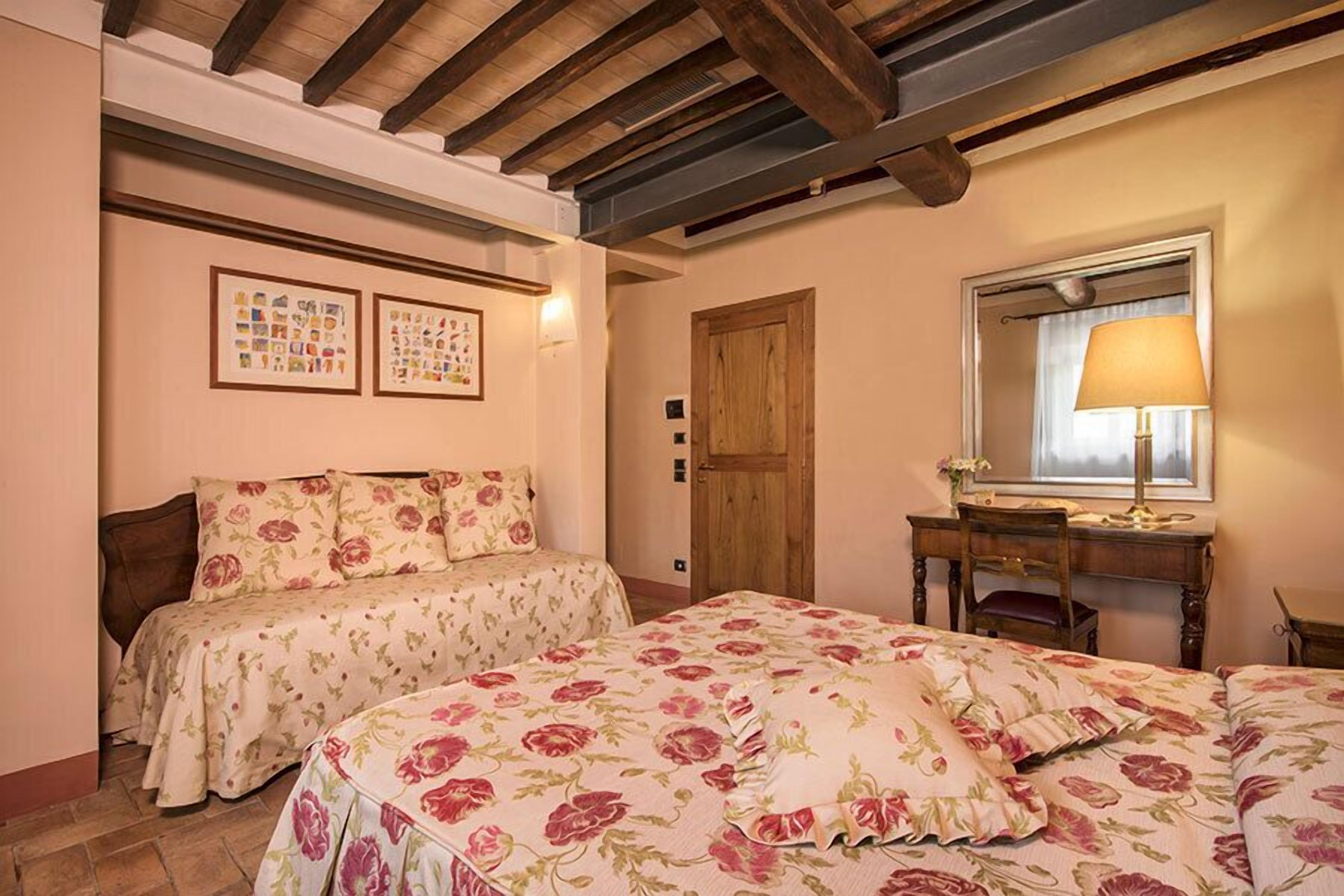 Un dormitorio con dos camas, un escritorio de madera, una silla, un espejo y cuadros en la pared.