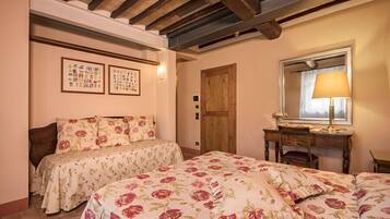Un dormitorio con dos camas, un escritorio de madera, una silla, un espejo y cuadros en la pared.