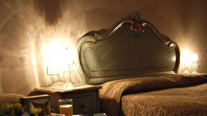 Ein Hotelzimmer mit einem klassischen Bett, einem Nachttisch mit Lampe und einem Tablett mit Frühstücksgegenständen.