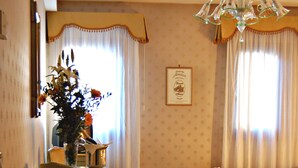 Ein Hotelzimmer mit Bett, Sessel, einem kleinen Tisch mit Vase und einer Chandelier.