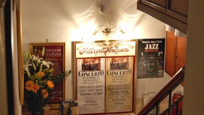 Eine Treppe mit hölzernem Geländer, einer Wand mit gerahmten Postern und einer Chandelier.