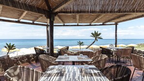 An outdoor dining area with tables and chairs, overlooking the ocean. - Baia del Sole Resort (Ricadi)