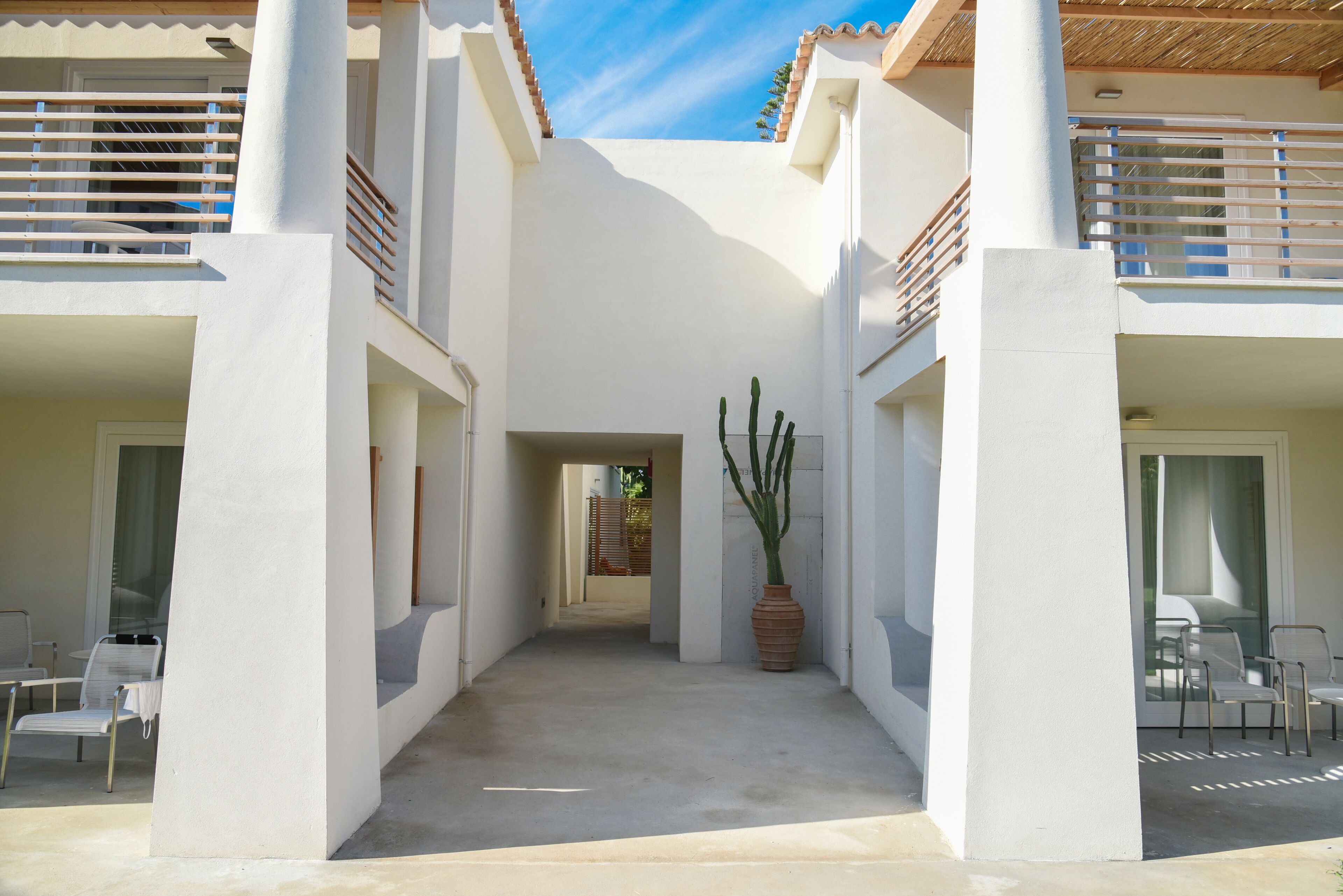 Un edificio moderno con un patio central, paredes blancas y una gran planta de cactus.