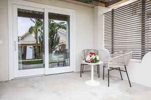 A balcony with a white table and two wicker chairs, a glass door, and a window with horizontal blinds. - Baia del Sole Resort (Ricadi)