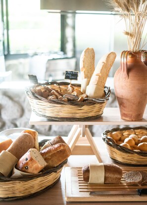 A table with various breads and pastries, including a basket of breadsticks, a loaf of bread, and a jar of jam. - Baia del Sole Resort (Ricadi)