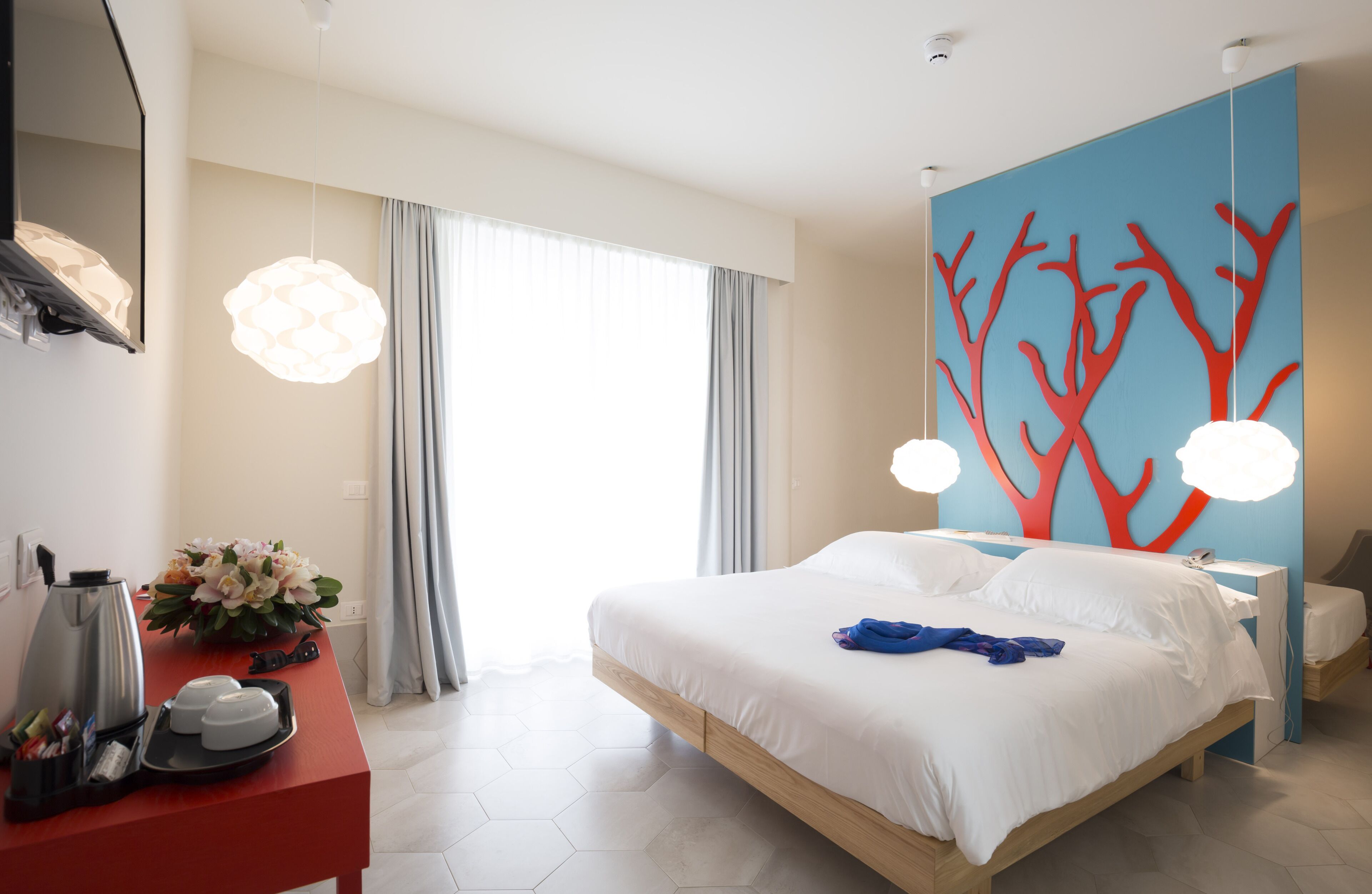 Een moderne hotelkamer met een groot bed, een bureau met een koffiezetapparaat en een decoratieve wand.
