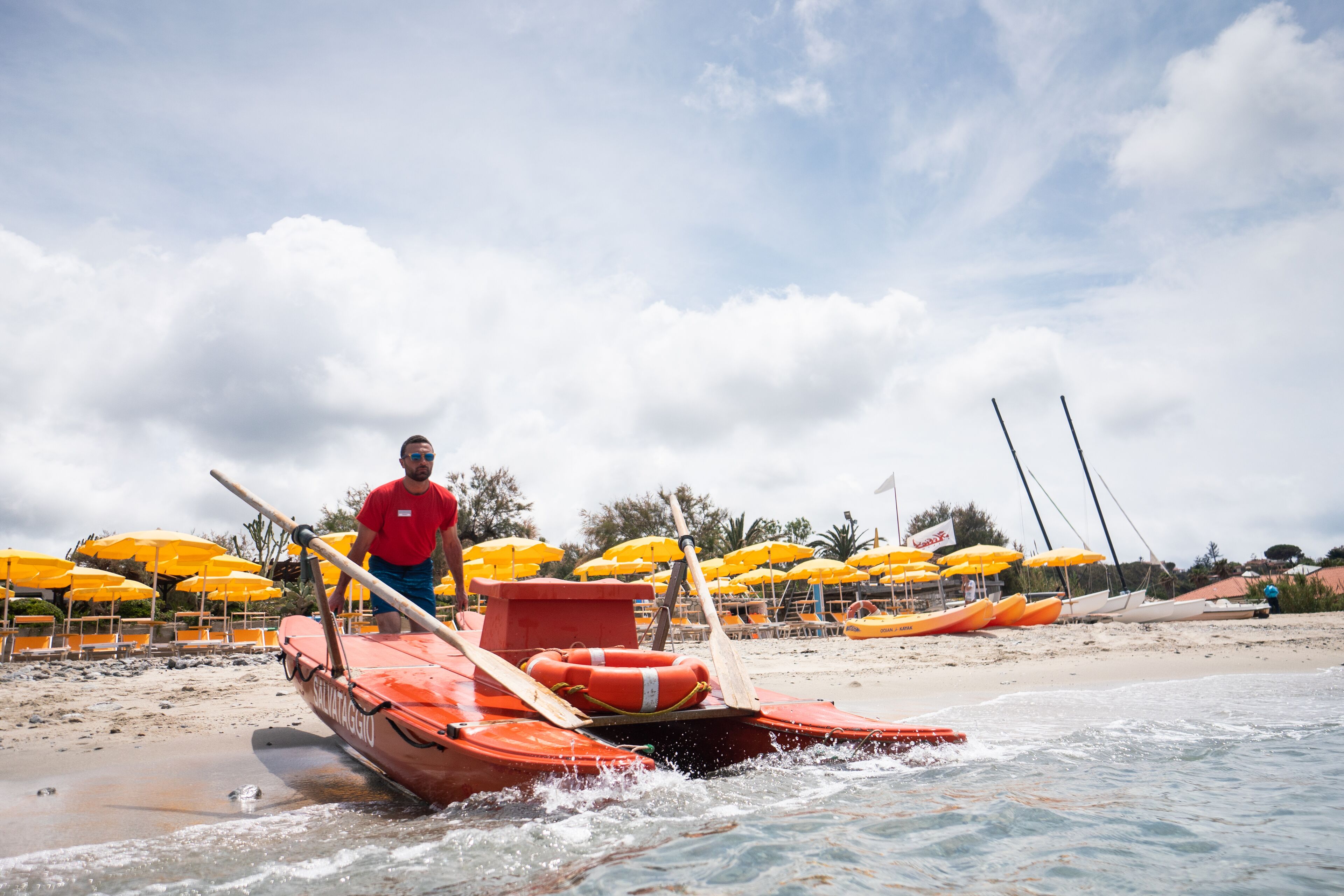 Una playa con varios barcos y sombrillas amarillas.