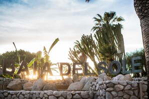 A sign with the words "BAJA DEL SOL" surrounded by rocks and palm trees. - Baia del Sole Resort (Ricadi)