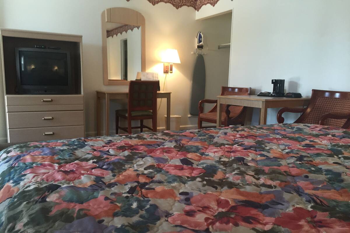 Ett hotellrum med en säng, en tv, ett skrivbord och en stol.