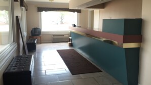 A kitchen with a built-in counter, a bench, a television, and a window with a view of the outside. - Prestige Inn West Lafayette (West Lafayette)