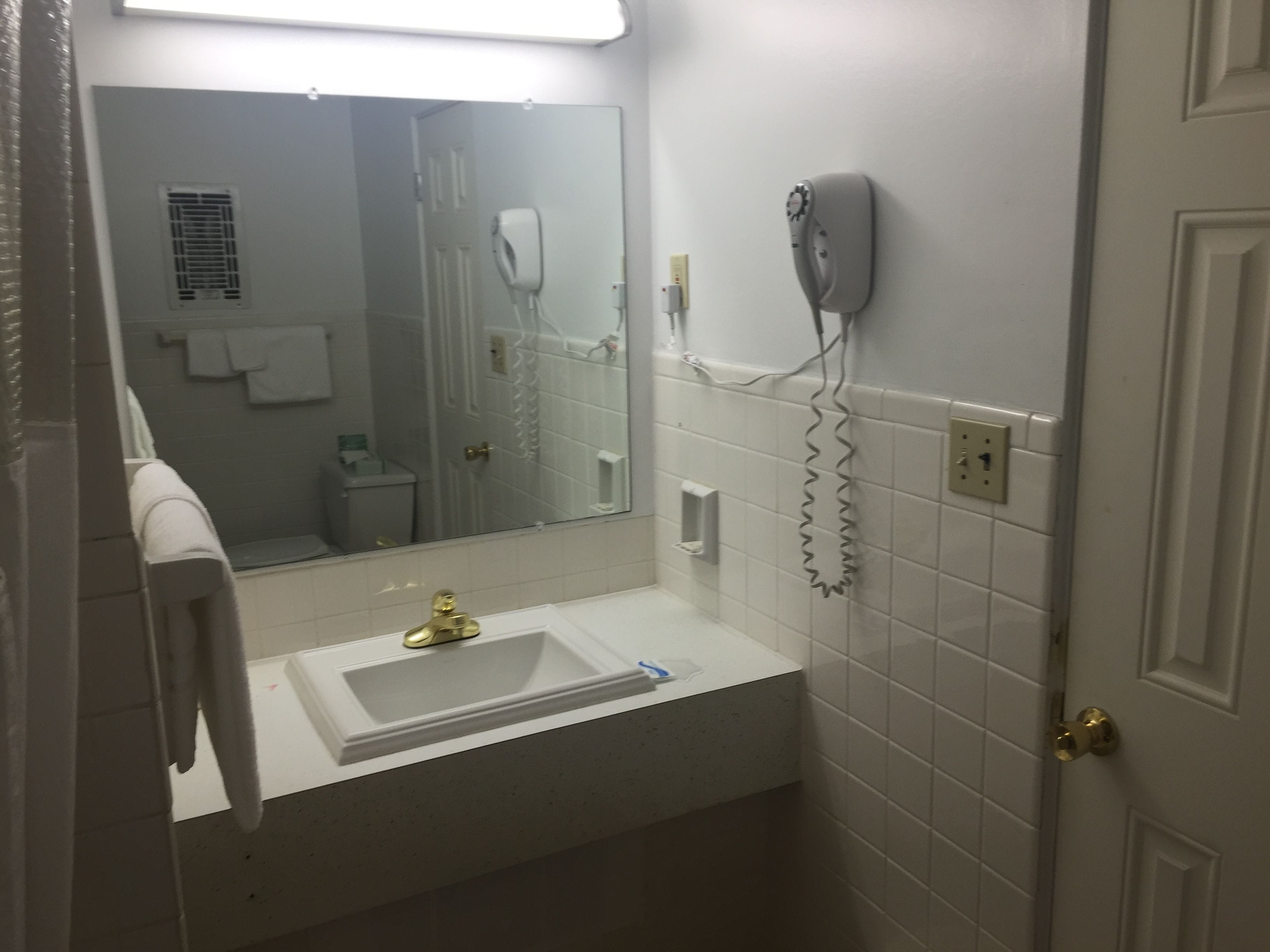A bathroom with a white sink, a mirror, a hairdryer, and a towel rack.