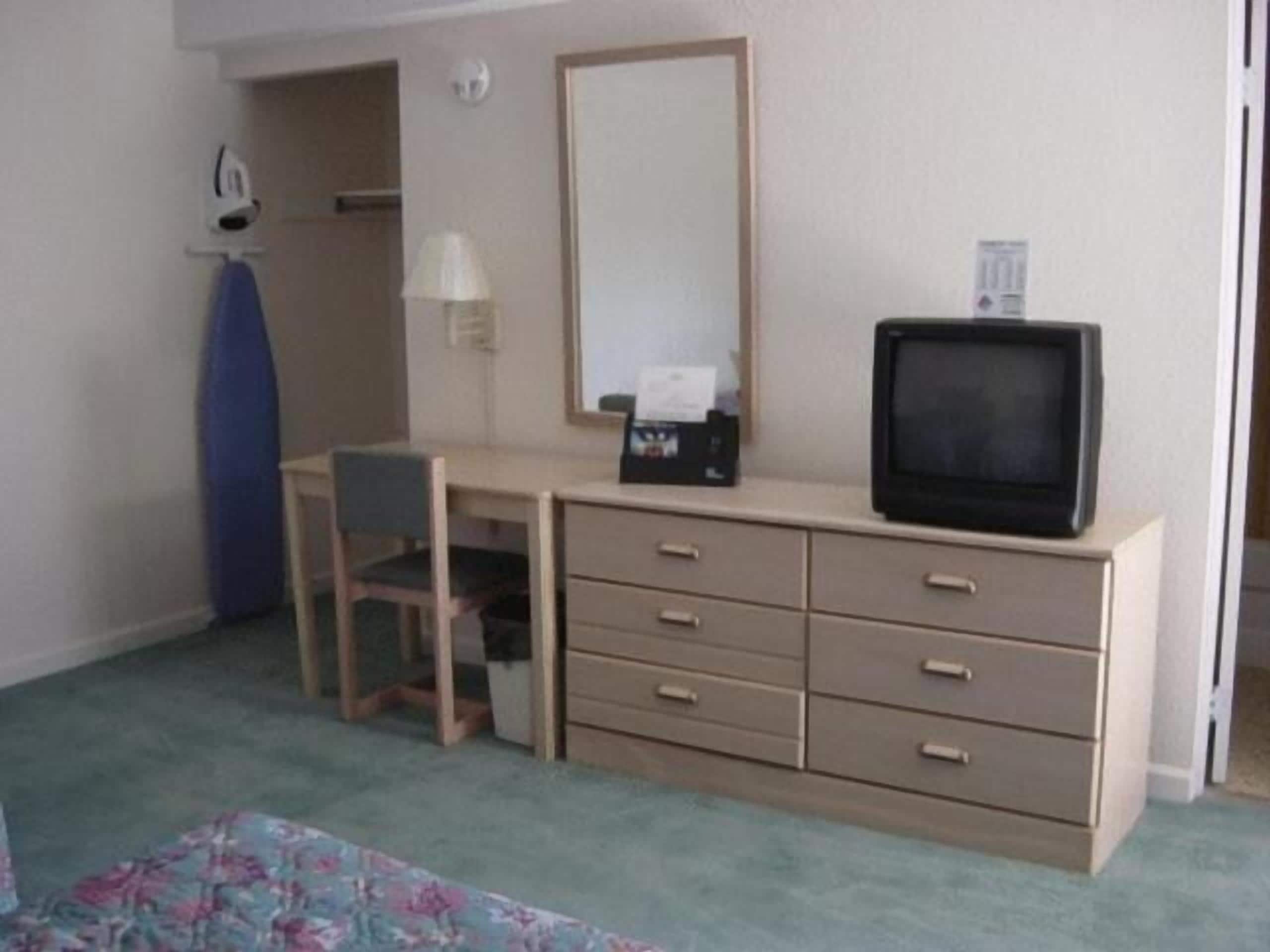 Une petite pièce simple, avec un bureau, une chaise et un téléviseur.