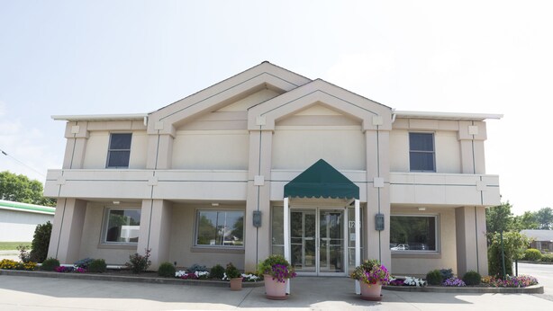A two-story building with a symmetrical facade, large windows, and a green awning over the entrance. - Prestige Inn West Lafayette (West Lafayette)