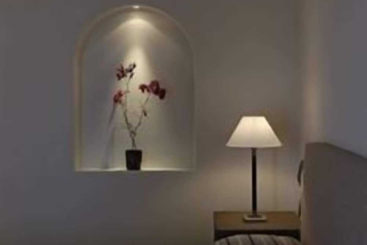 Ein Schlafzimmer mit einem Bett, einem Nachttisch mit Lampe und einem an der Wand montierten Regal mit einer Topfpflanze.