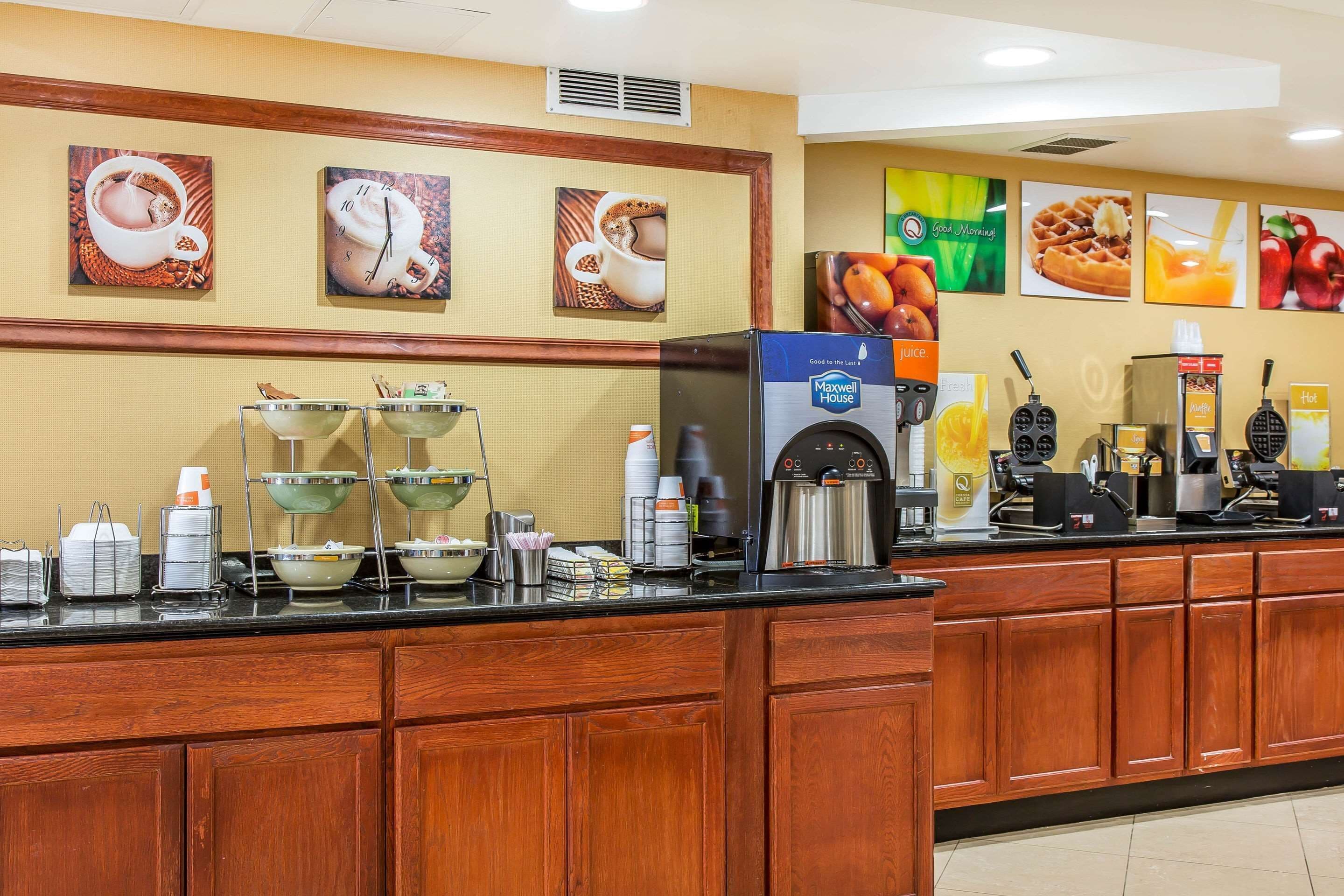 A breakfast bar with coffee machines, a juice dispenser, and a waffle maker.
