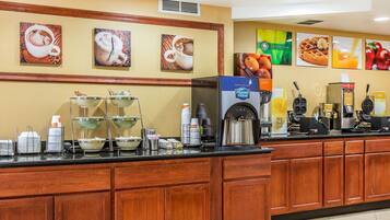 A breakfast bar with coffee machines, a juice dispenser, and a waffle maker.