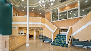 Eine geräumige Lobby mit einer Rezeption, einer Treppe und Sitzbereichen.