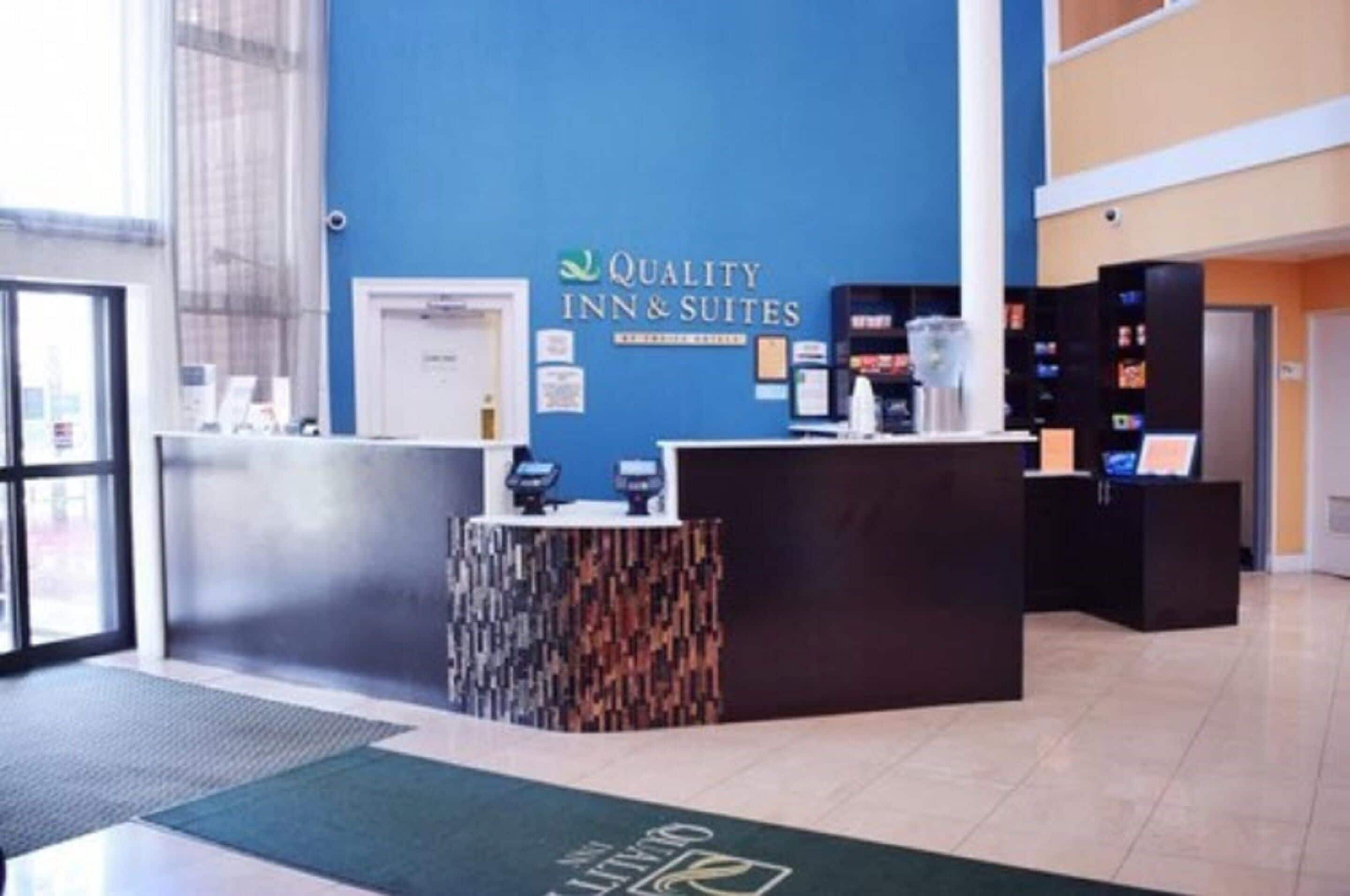 A reception area with a blue wall, a reception desk, and a digital display.