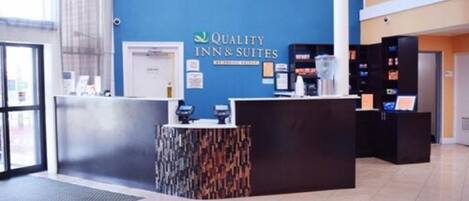A reception area with a blue wall, a reception desk, and a digital display.