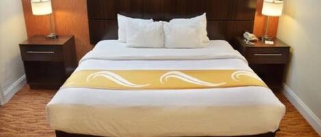 A hotel room with a large bed, two bedside tables, and lamps.