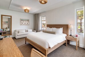 A hotel room with a large bed, a wooden nightstand, a bedside table, a desk, a chair, a sofa, a large window, and a mirror. - Liberty Park Hotel South Beach (Miami Beach)