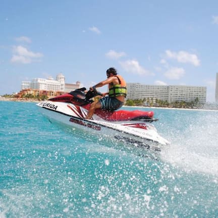 A jet ski on a clear blue sea with buildings in the background.