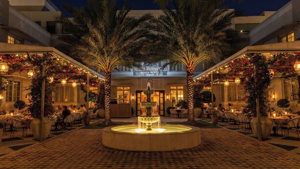 A hotel courtyard with a central fountain, palm trees, and outdoor seating areas. - Liberty Park Hotel South Beach (Miami Beach)